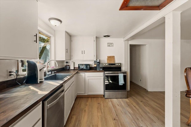 kitchen with wooden counters, white cabinetry, appliances with stainless steel finishes, sink, and light hardwood / wood-style flooring