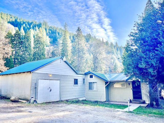 view of front of property with a detached garage and metal roof