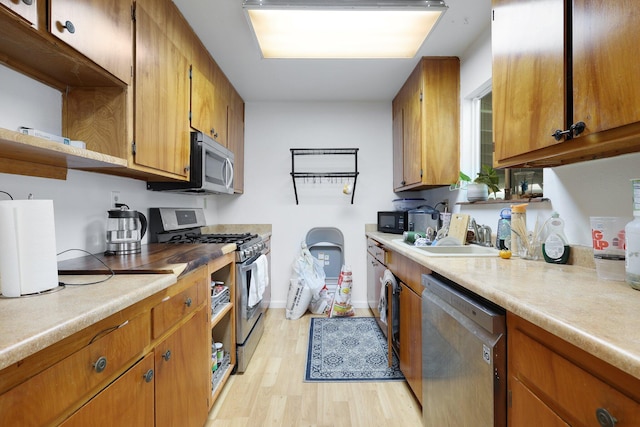 kitchen with appliances with stainless steel finishes, light hardwood / wood-style floors, and sink