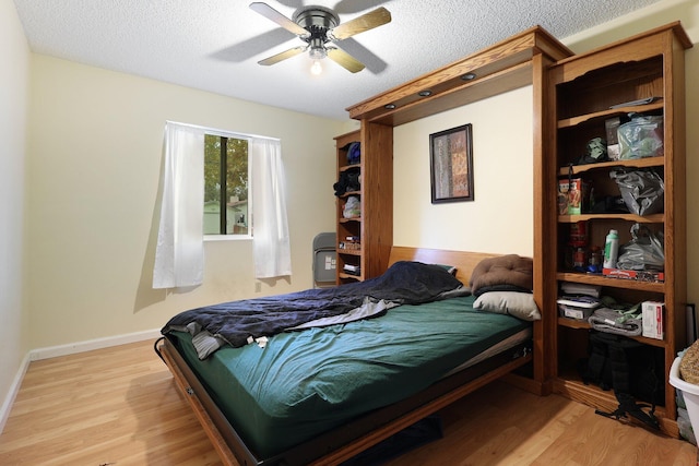 bedroom with ceiling fan, a textured ceiling, and light wood-type flooring