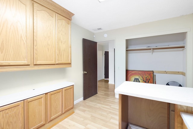 interior space with light brown cabinets, kitchen peninsula, and light hardwood / wood-style flooring