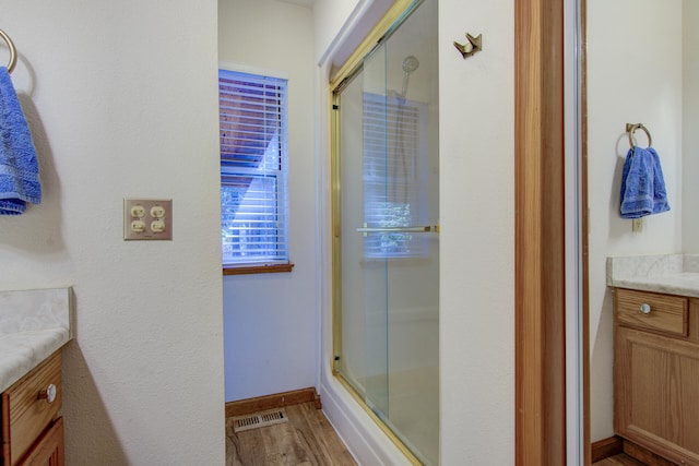 bathroom with walk in shower, vanity, and hardwood / wood-style flooring