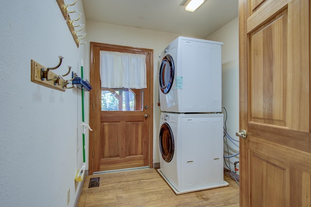 laundry area with light wood-type flooring and stacked washer and clothes dryer