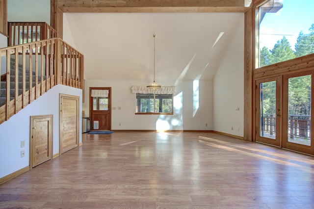 unfurnished living room with wood-type flooring and high vaulted ceiling