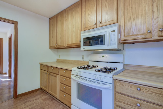 kitchen with light wood-type flooring, light brown cabinetry, and white appliances