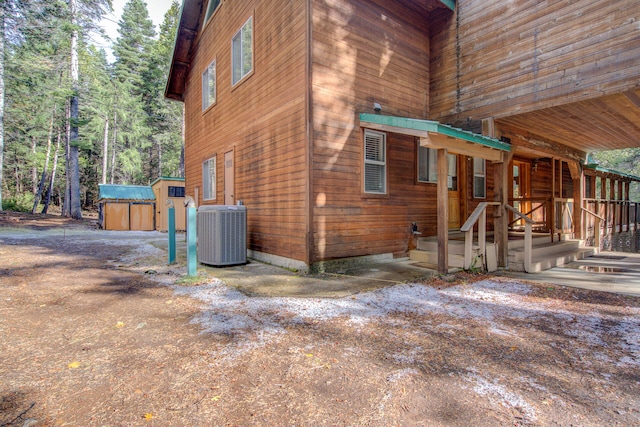 view of side of home with a shed and central AC