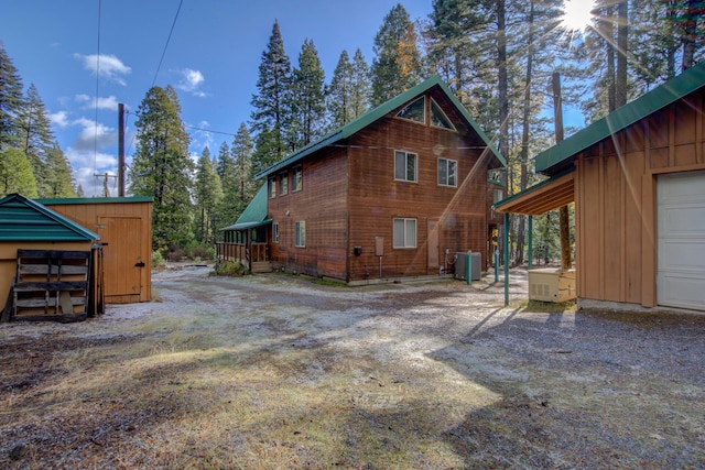 back of house with a storage unit and central AC