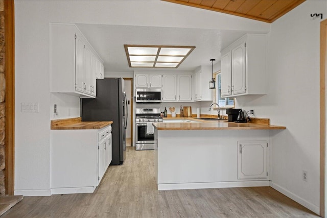 kitchen featuring sink, stainless steel appliances, kitchen peninsula, lofted ceiling, and white cabinets