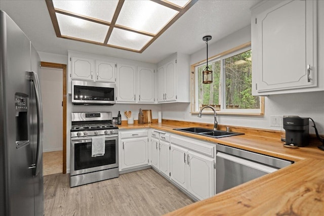 kitchen with light hardwood / wood-style floors, sink, white cabinetry, and stainless steel appliances