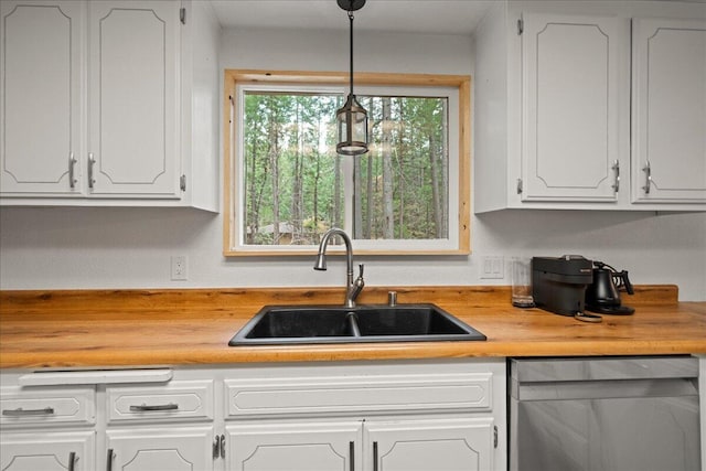 kitchen featuring sink, decorative light fixtures, dishwasher, white cabinets, and butcher block counters