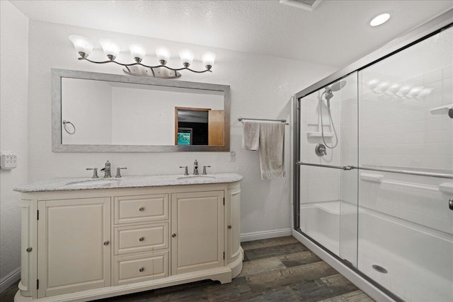 bathroom with a shower with door, vanity, wood-type flooring, and a textured ceiling