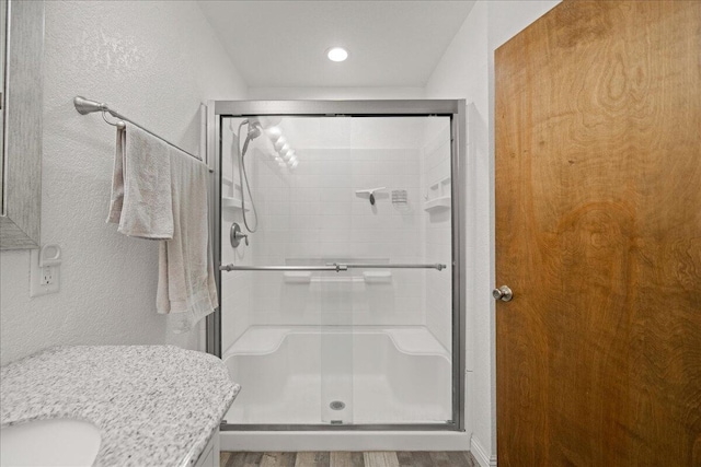 bathroom with hardwood / wood-style flooring, vanity, and a shower with door