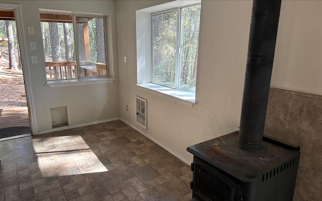 doorway to outside featuring a wood stove, a wealth of natural light, and heating unit