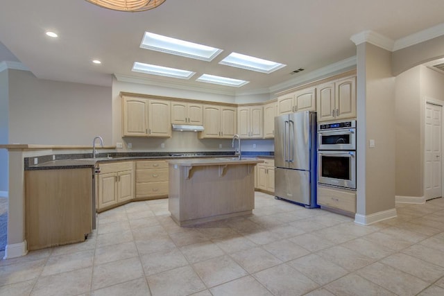 kitchen with light brown cabinets, a breakfast bar area, and appliances with stainless steel finishes