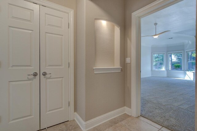 corridor featuring light colored carpet and crown molding