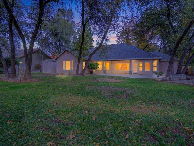 view of front of property featuring a patio area, a storage shed, and a lawn