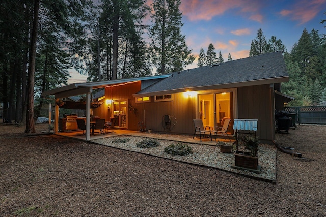 back house at dusk featuring a patio