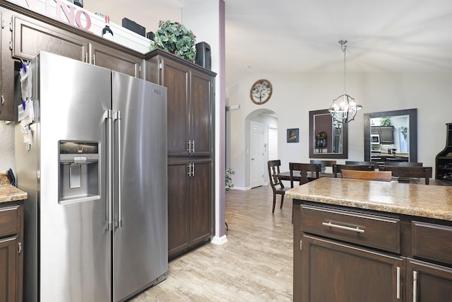 kitchen with stainless steel refrigerator with ice dispenser, light wood-type flooring, dark brown cabinetry, hanging light fixtures, and lofted ceiling