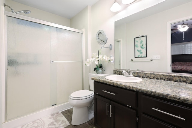 bathroom featuring ceiling fan, hardwood / wood-style floors, toilet, a shower with door, and vanity