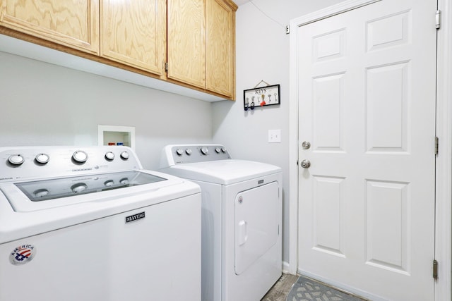 laundry area with separate washer and dryer and cabinets