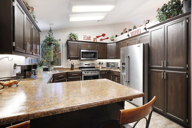 kitchen with dark brown cabinetry, sink, stainless steel appliances, kitchen peninsula, and lofted ceiling