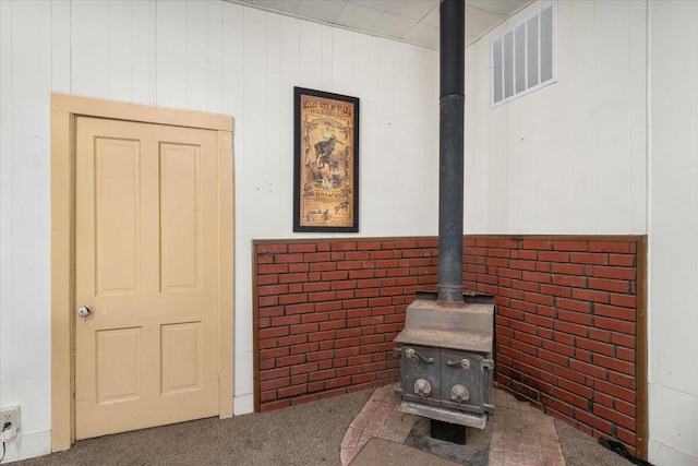 interior details with carpet flooring, a wood stove, and wooden walls