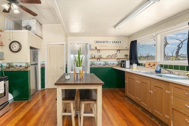 kitchen featuring ceiling fan, a center island, dark wood-type flooring, stainless steel range oven, and a breakfast bar