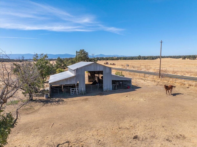 view of front of home featuring a mountain view, a rural view, and an outbuilding