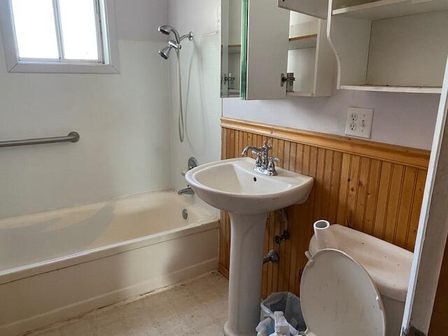 bathroom featuring wooden walls and shower / bathtub combination