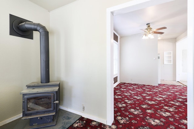 living room with ceiling fan, a wood stove, and carpet floors