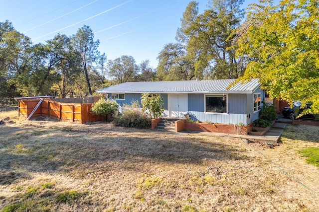 ranch-style home featuring fence and metal roof