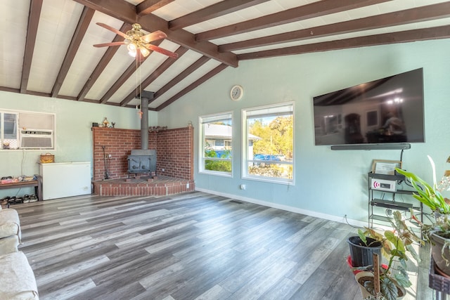 unfurnished living room featuring hardwood / wood-style floors, vaulted ceiling with beams, ceiling fan, and a wood stove