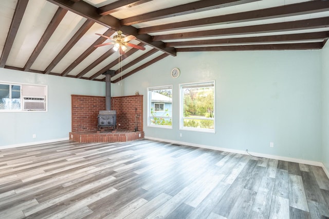 unfurnished living room featuring a wood stove, baseboards, wood finished floors, and vaulted ceiling with beams