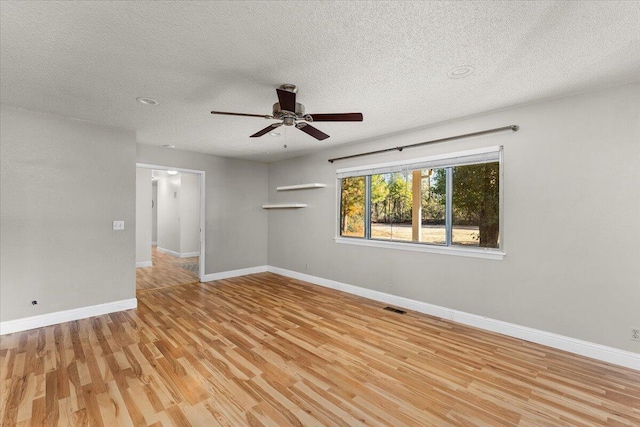 empty room with ceiling fan, light hardwood / wood-style floors, and a textured ceiling