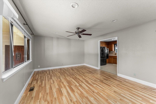 spare room featuring ceiling fan, a textured ceiling, and light hardwood / wood-style flooring