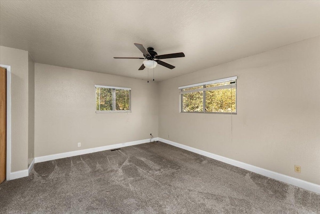 unfurnished room with ceiling fan, a textured ceiling, and dark colored carpet