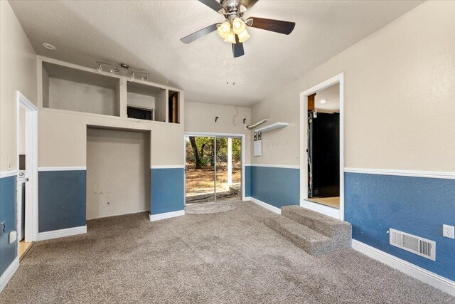 unfurnished living room featuring a textured ceiling, carpet floors, and ceiling fan