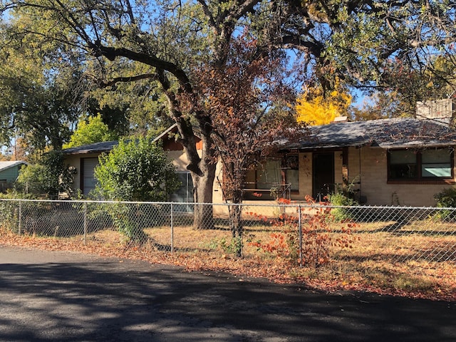 view of property hidden behind natural elements featuring a fenced front yard and an attached garage