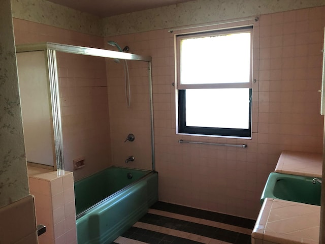 bathroom with combined bath / shower with glass door, tile walls, and vanity