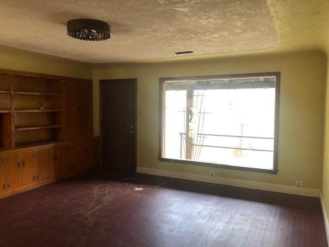 unfurnished room with a wealth of natural light, a textured ceiling, and baseboards