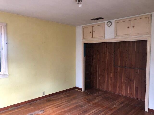 unfurnished bedroom with dark wood-style flooring, a closet, visible vents, and baseboards