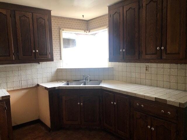 kitchen with dark brown cabinets, backsplash, and a sink