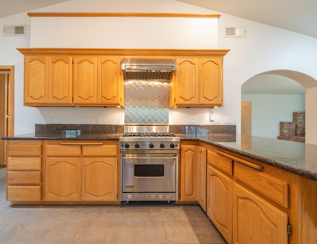 kitchen with lofted ceiling, wall chimney exhaust hood, premium range, and dark stone countertops