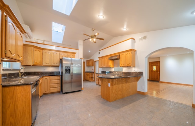 kitchen featuring a skylight, high vaulted ceiling, appliances with stainless steel finishes, exhaust hood, and light wood-type flooring