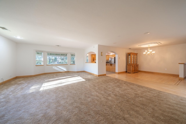 empty room with a notable chandelier and light carpet