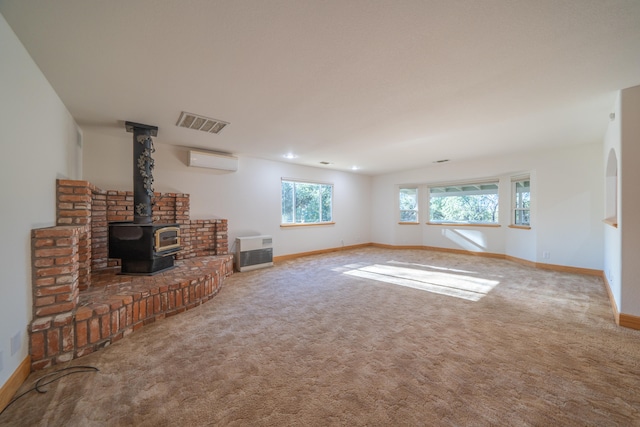 unfurnished living room featuring carpet, a wood stove, and an AC wall unit