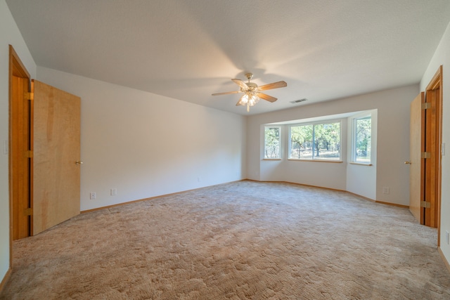 carpeted spare room with a textured ceiling and ceiling fan