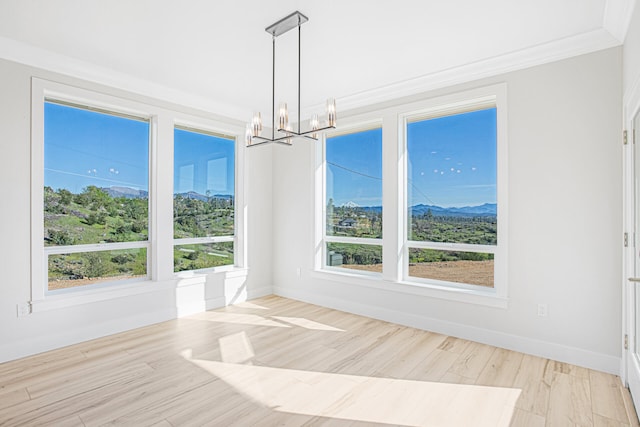 unfurnished dining area featuring an inviting chandelier, light hardwood / wood-style floors, and ornamental molding