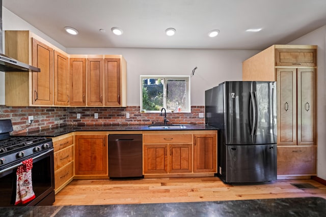 kitchen with sink, wall chimney exhaust hood, stainless steel appliances, tasteful backsplash, and light hardwood / wood-style flooring