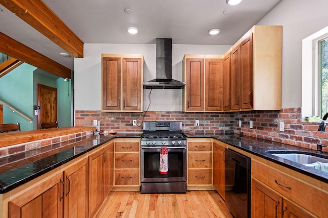 kitchen with wall chimney exhaust hood, sink, light hardwood / wood-style flooring, black dishwasher, and stainless steel range with gas cooktop